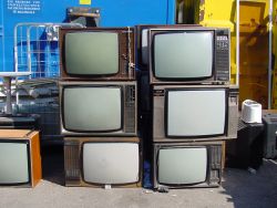 Sieben alte Fernseher stehen in zwei Reihen gestapelt. Elektronikschrott